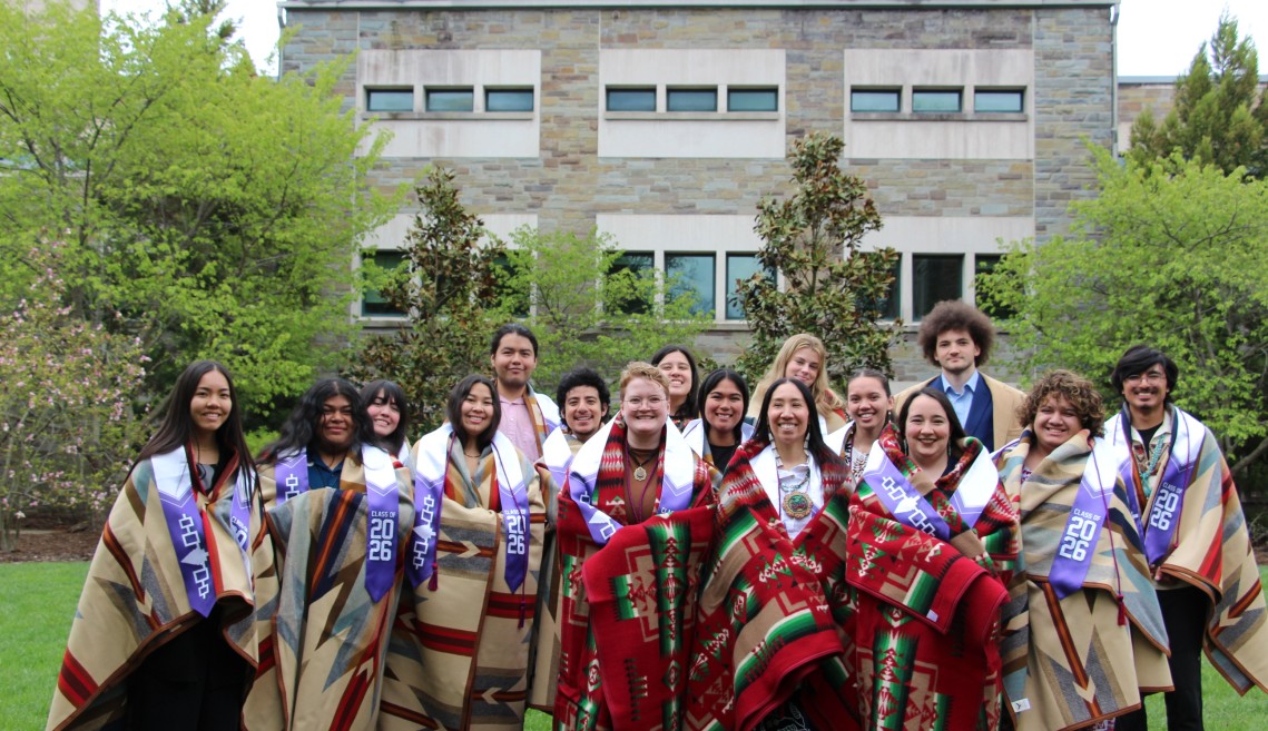 All grads stand smiling with their blankets 