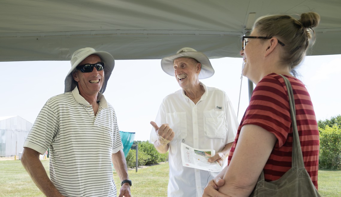 Three people are talking and laughing at a farm