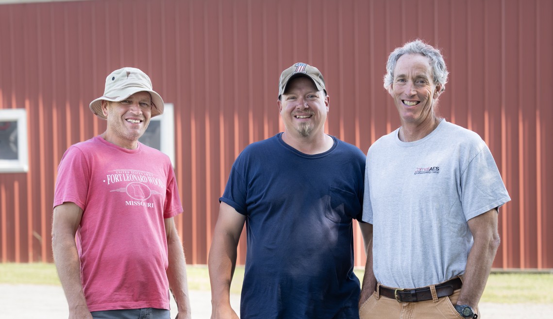 The three-people farm crew in front of a barn