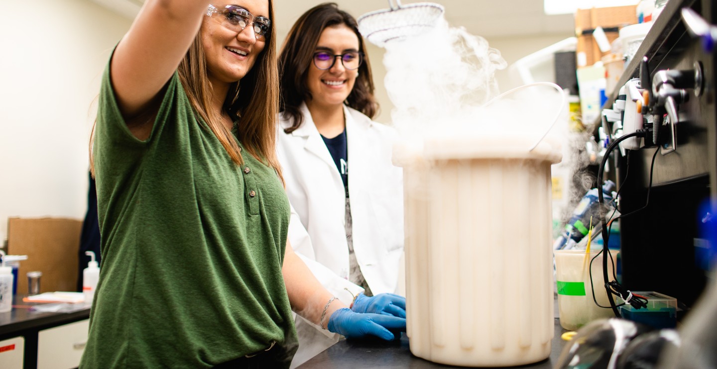Two women in a lab mixing liquids.