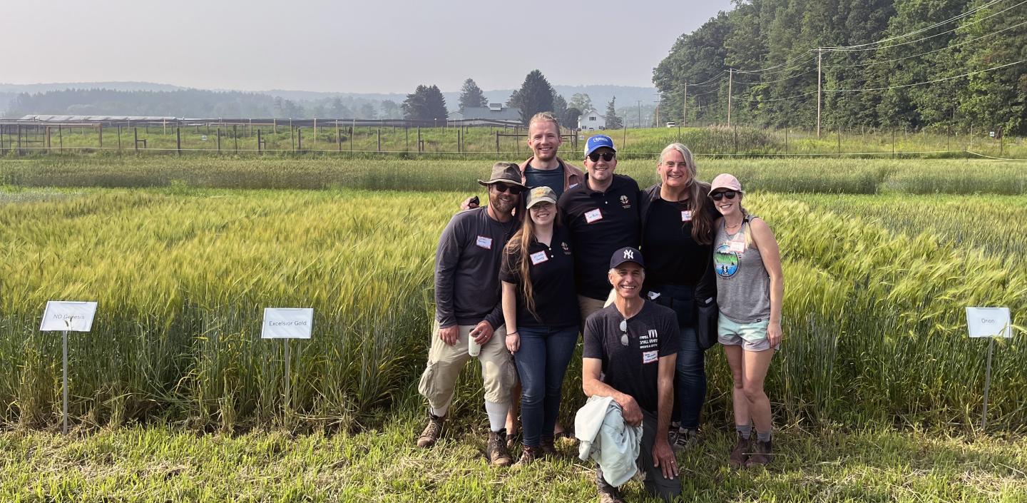 Group smiling in front of barley plots