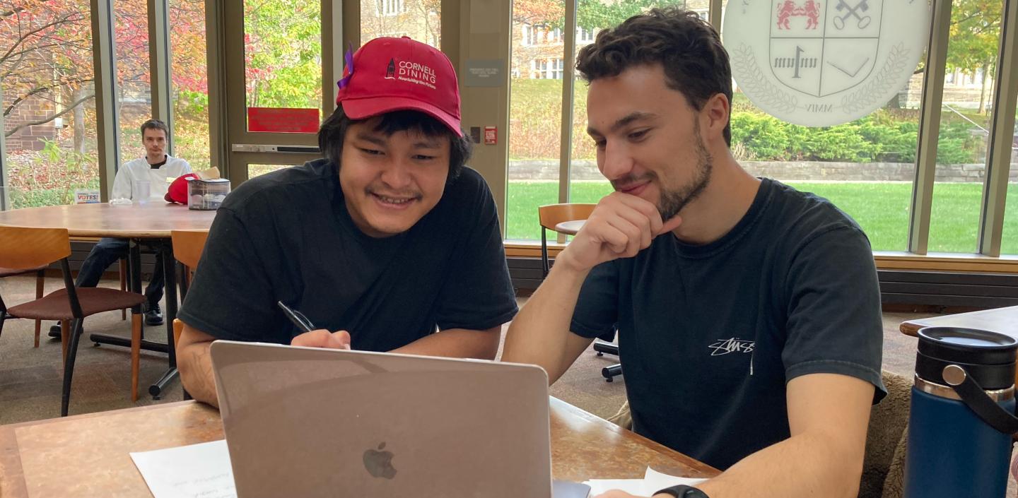 Two individuals work on laptop
