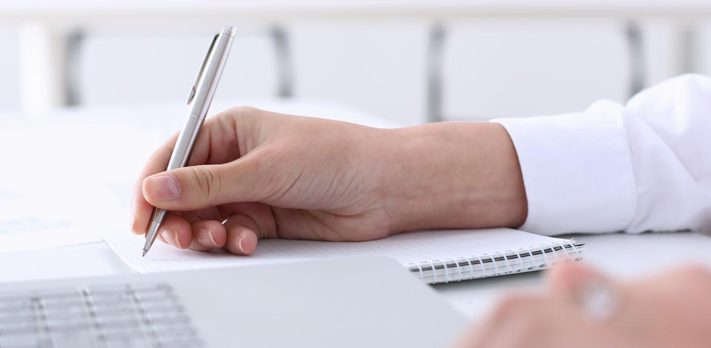 A hand is revising a document with a pen