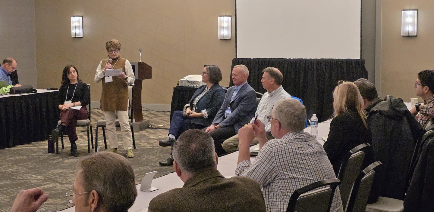 Several people sitting in a conference room listening to a speaker presentation.