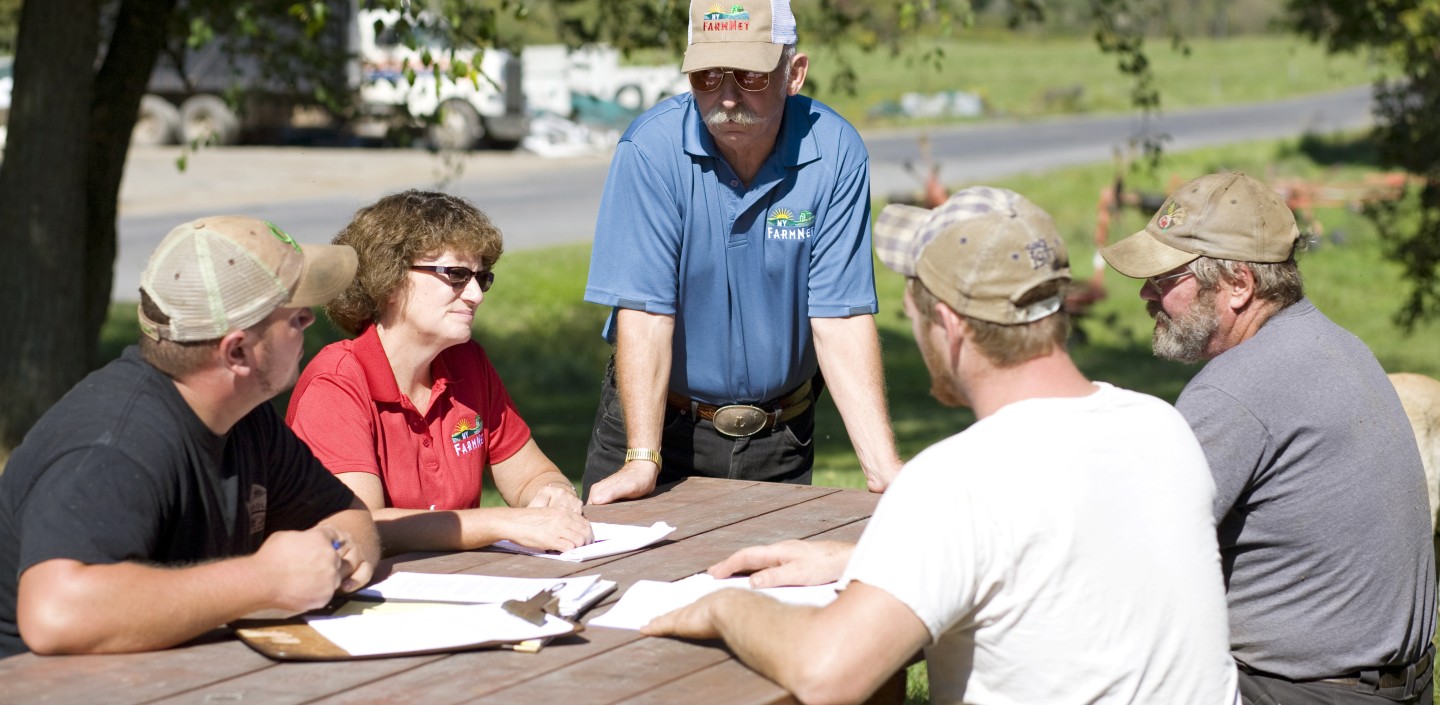 A man looking over forms with other people sitting around a picnic table. 