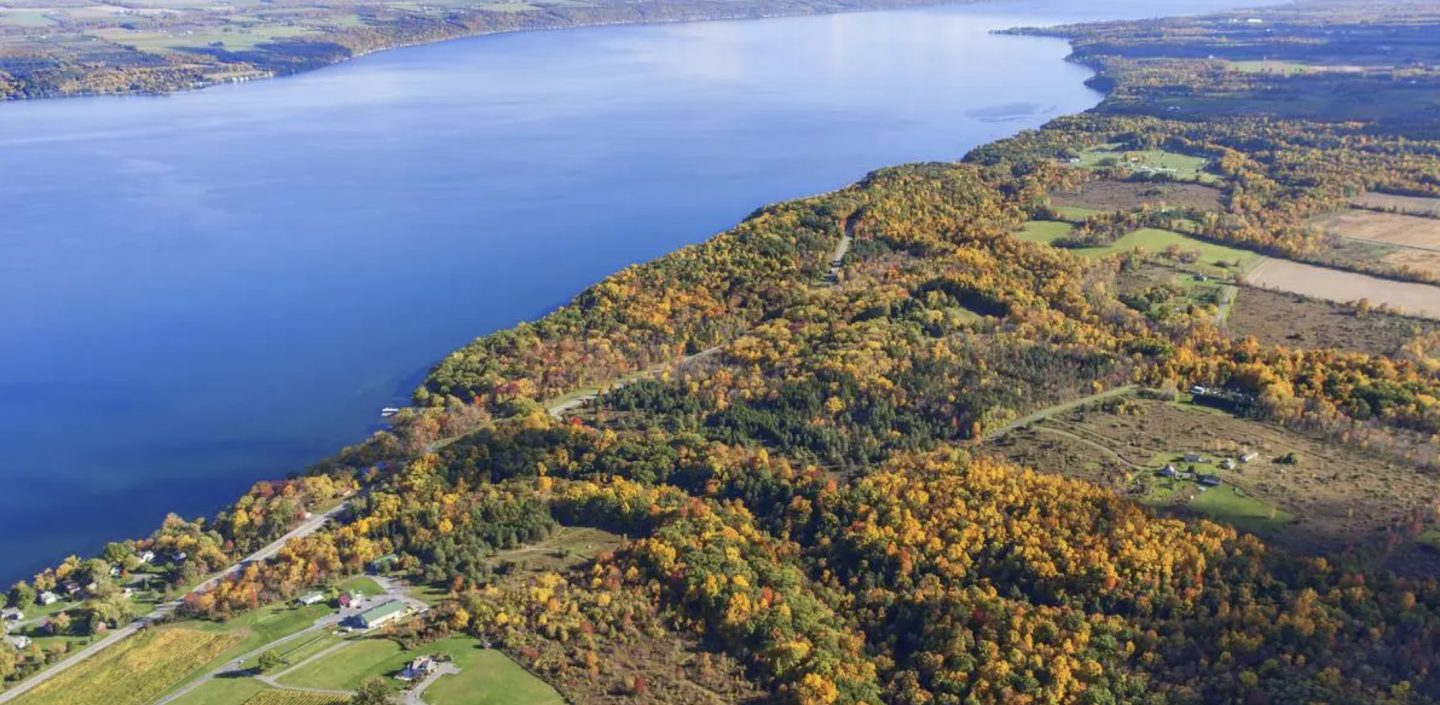 Aerial photograph of a large lake with some woods and farmland surrounding it in fall.