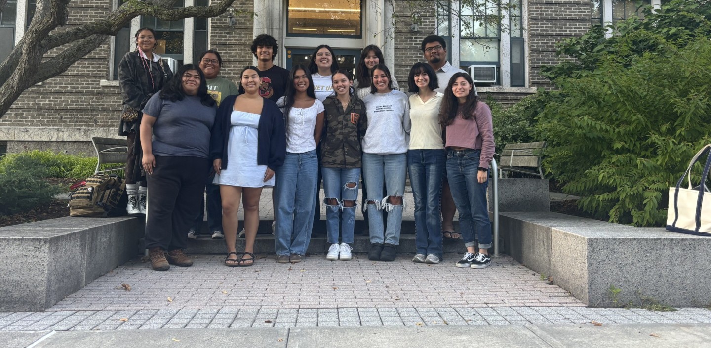 Student leaders stand smiling in front of Caldwell Hall.