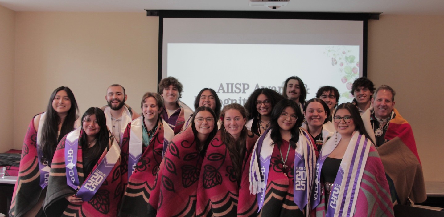 Students draped in blankets stand in a group.
