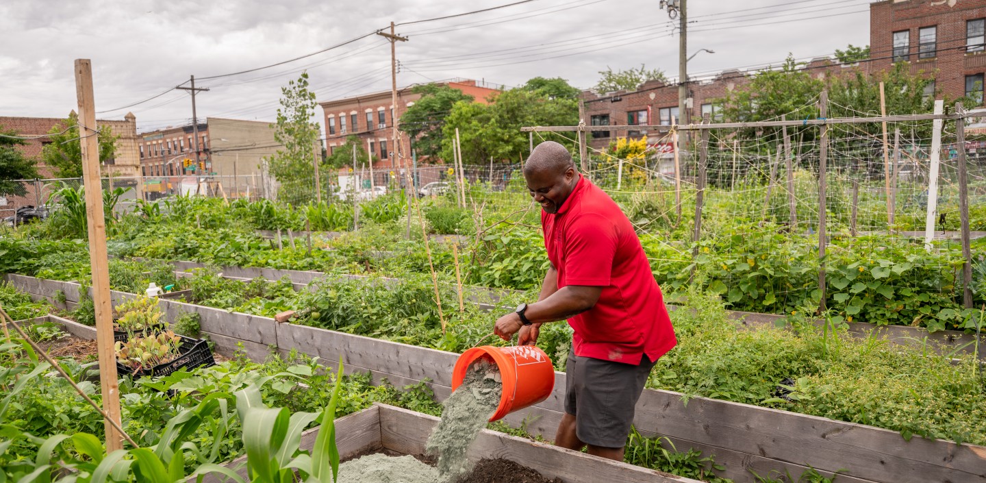 a man in a red shirt working in a garden in the city