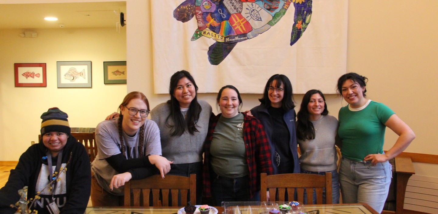 People stand in front of a table smiling.