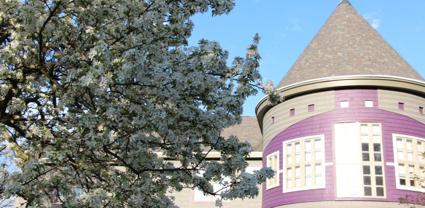 Akwe:kon with a blooming tree in front of it.