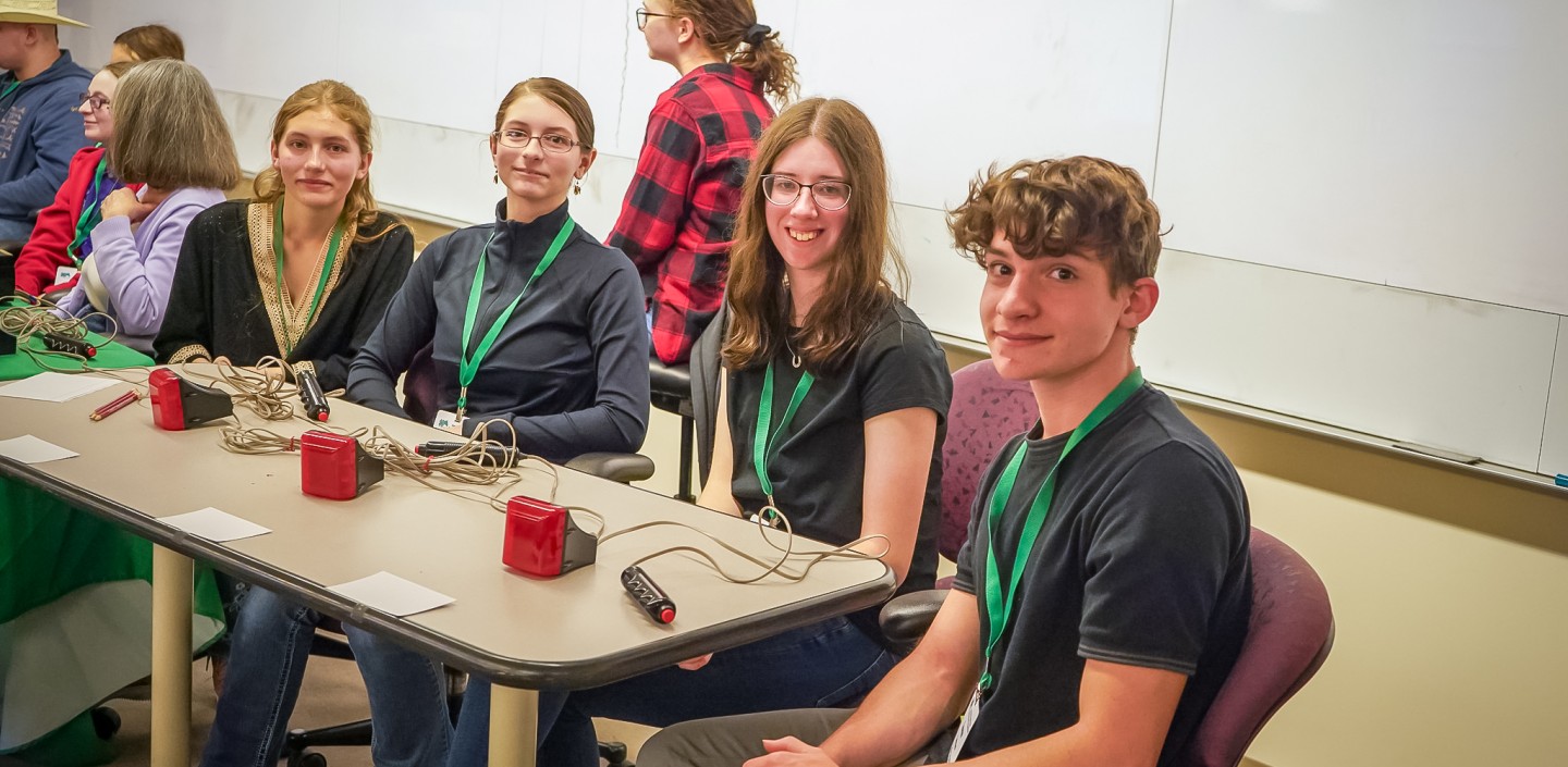 four teens sit behind a table