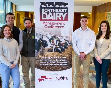 students and faculty pose in front of an event banner