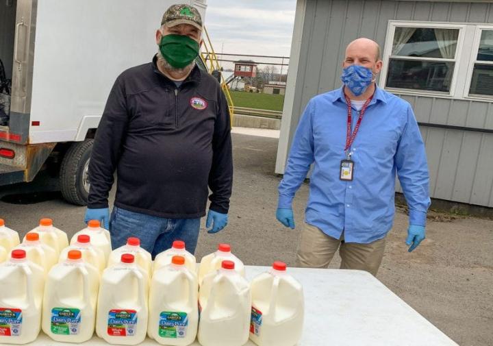 Two men standing with gallons of milk for donation