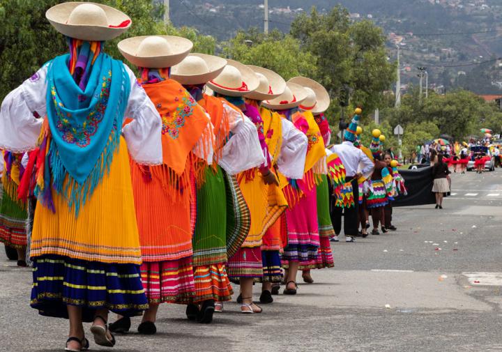Women dance in the street wearing colorful skirts