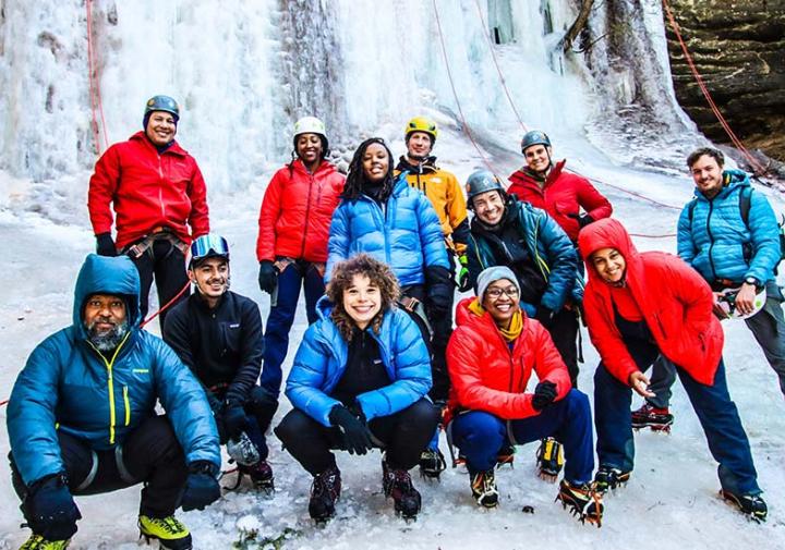 diverse group of outdoorsy people in front of frozen waterfall in winter