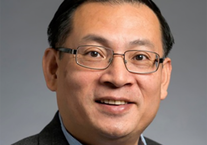 a close up of a man with glasses a blue shirt and gray jacket