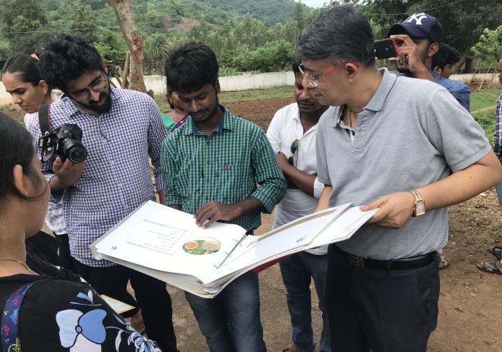 Three men look at a book
