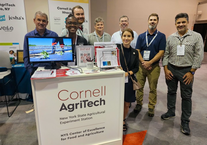 A group of people standing by a kiosk that says Cornell AgriTech