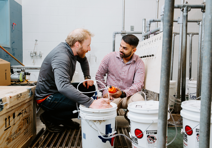 two researchers huddle around white buckets