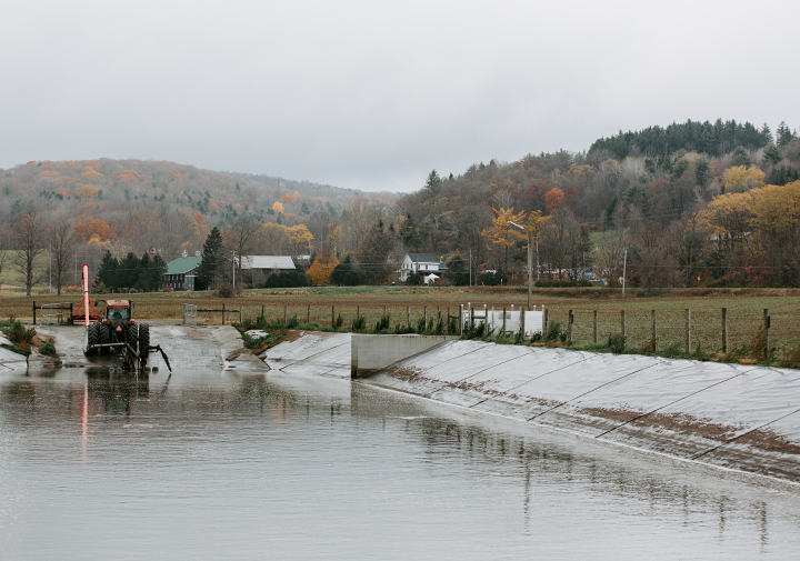 a large pool of water with a tractor in it and forested hills in the background