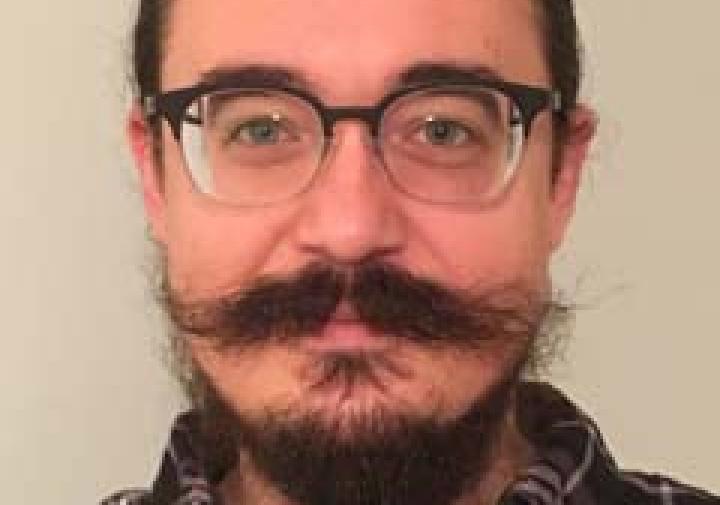 person in a plaid button down standing in front of a wall