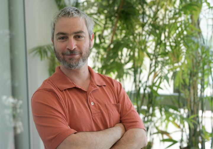 Person in a red shirt standing in front of plants