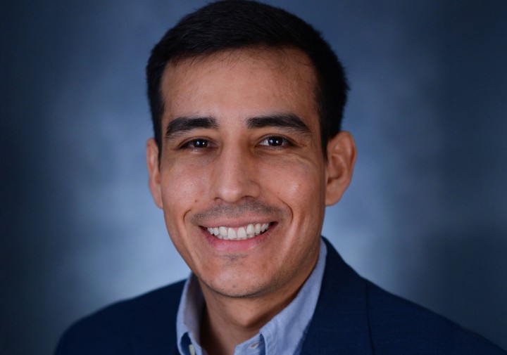 Headshot photo of Ivan Grijalva. He has dark hair and is wearing a dark blue suit. He is smiling.