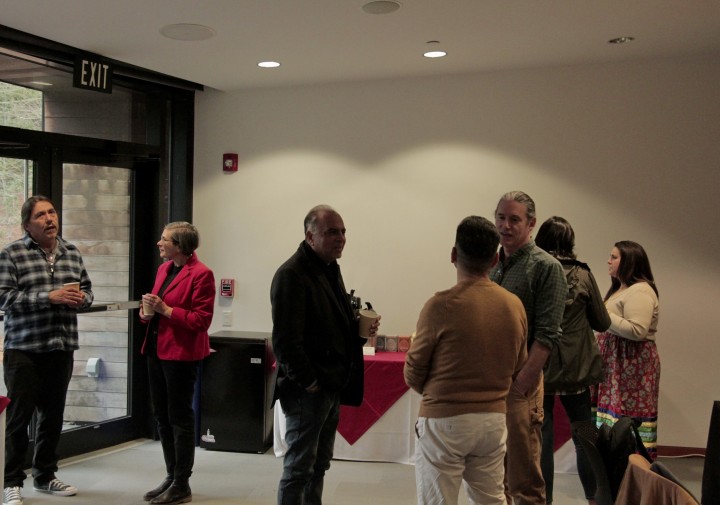 A group of people stand in front of buffet tables talking.