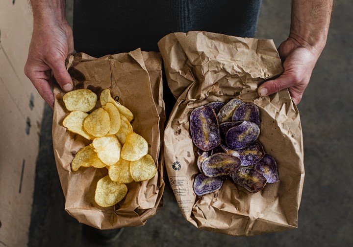 Hands holding white and blue potato chips