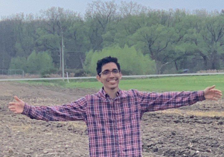 A man stands in a field with his arms outspread.