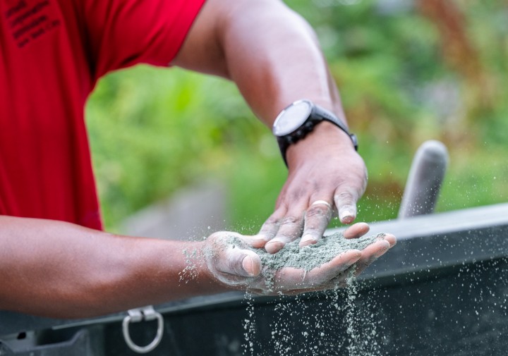 Kwesi Joseph - closeup of his  hands spreading soil amendment