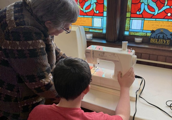 Elcsisin working with youth at sewing machine