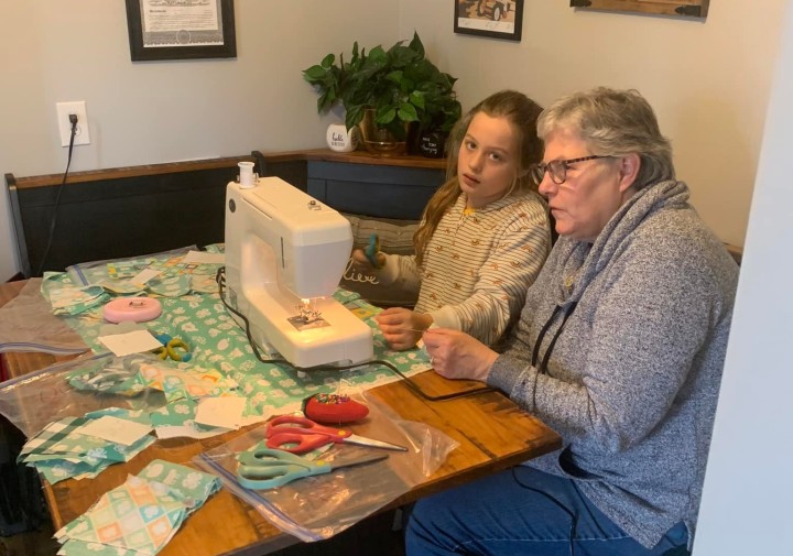 Linda sits at a sewing machine with a 4-H youth