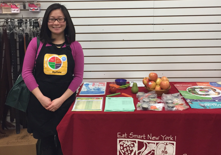 Mallory standing in front of a table displaying Eat Smart New York materials.