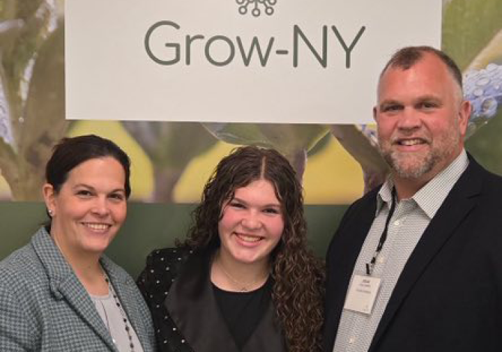Brian Aukema with daughter, posing in front of a Grow-NY banner.