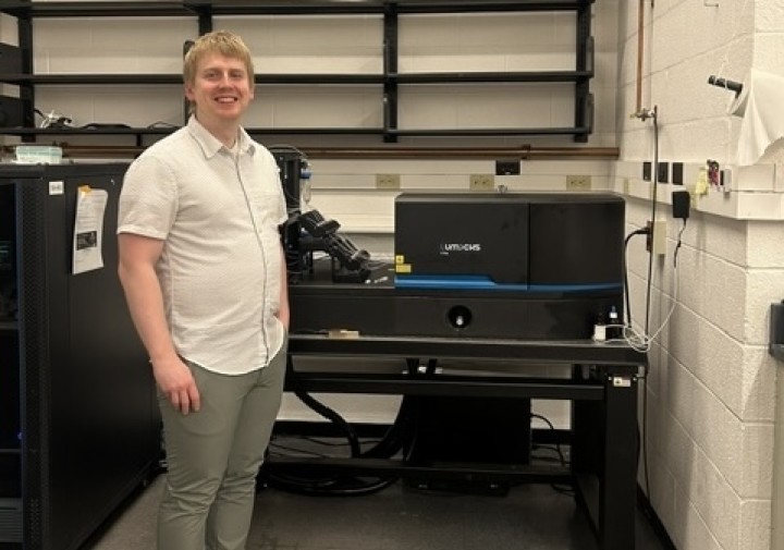 Mitch Woodhouse pictured with the Lumicks C-trap instrument in the Wang lab. 