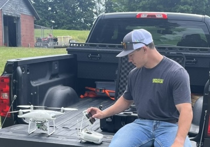 A man sits on a truck bed looking at equipment.