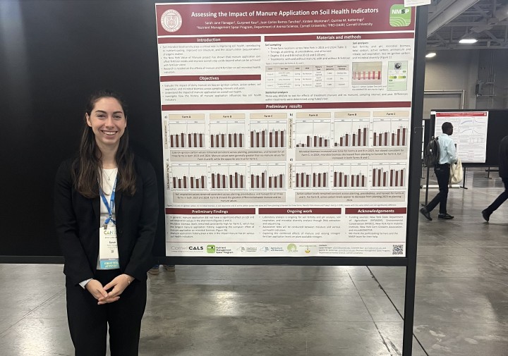 A woman stands next to a research poster, smiling.