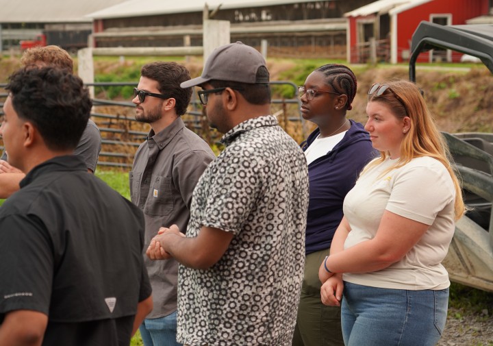 A group of young adults stands with their hands together, attention directed to the left.