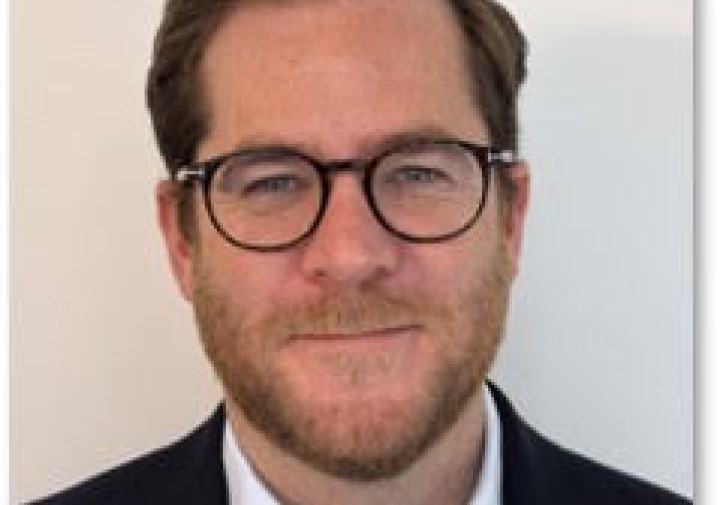 A photo of a professor with glasses, beard, and suit 