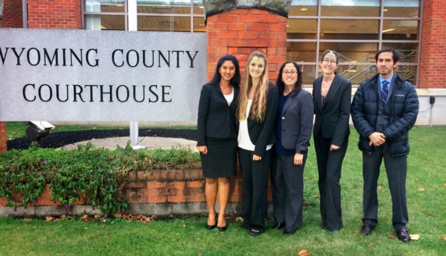 Four women and one male standing next to a sign for Wyoming County Courthouse