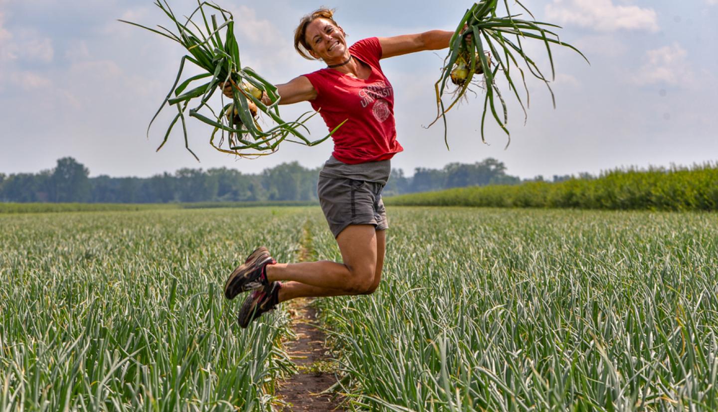 Hoepting jumping in a onion field holding onions