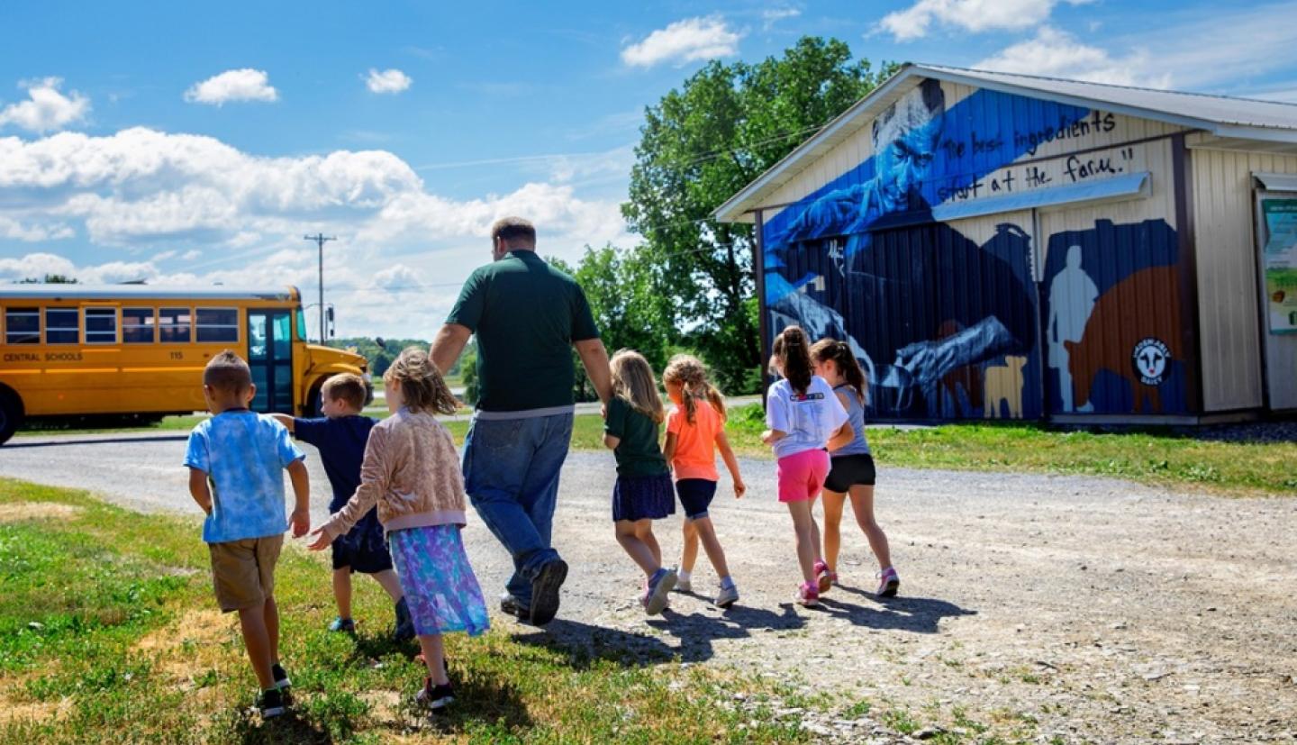 Nate Chittenden walks with children to a school bus