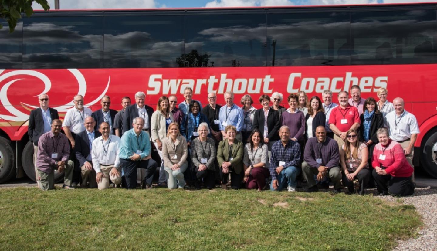 Tour group poses outside of bus
