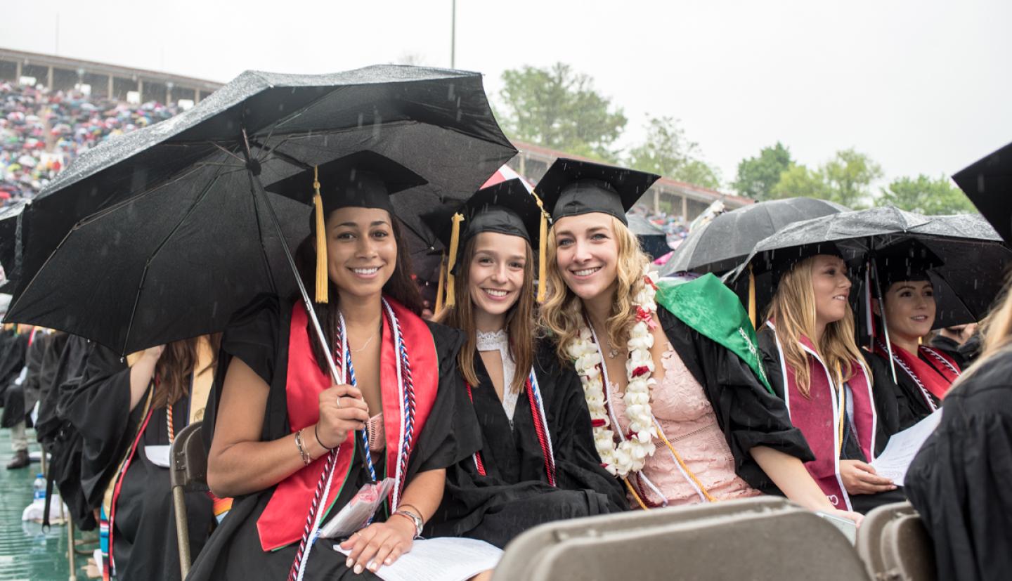 Graduates sitting with umbrellas