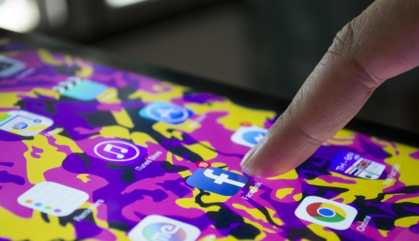 Phone user opening Facebook mobile app