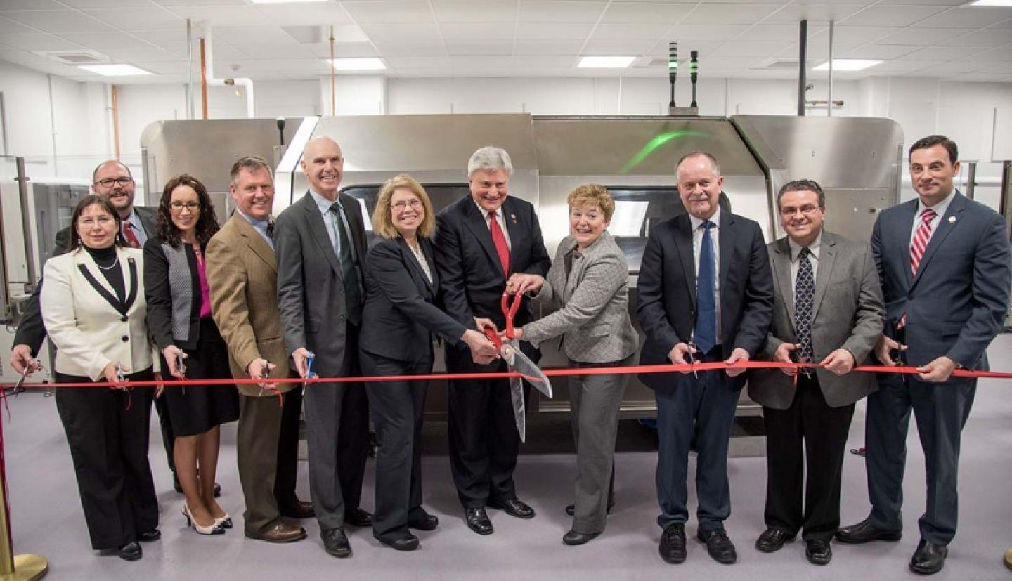 people standing around ribbon that is being cut