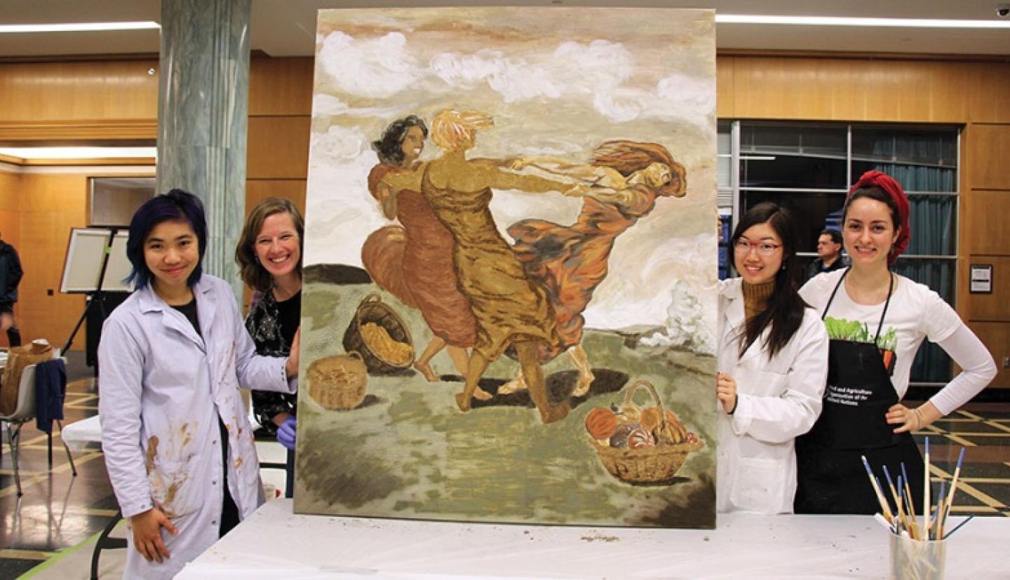 Students display their painting of three women in a field