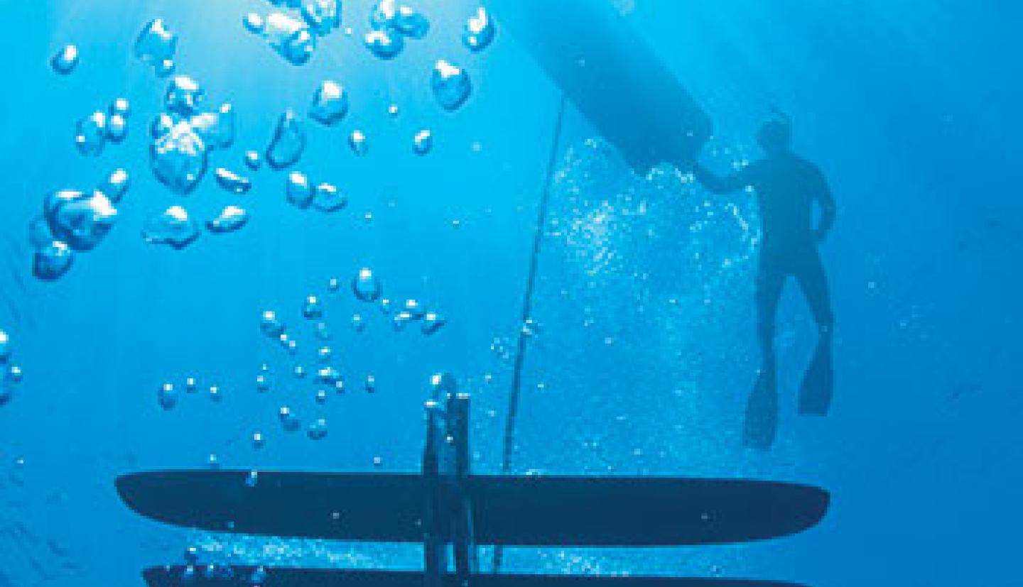 A man swims under water with an underwater drone